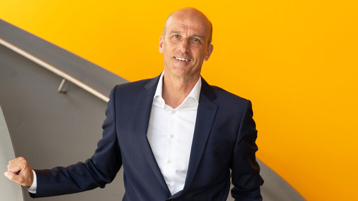 Werner Schmidbauer, der CEO der Schmidbauer Gruppe, im Anzug auf einer Treppe stehend.